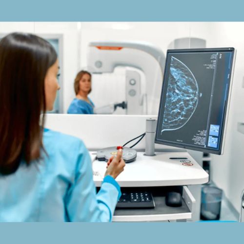Radiologist examines a breast scan on a monitor during a mammogram in a medical imaging room.
