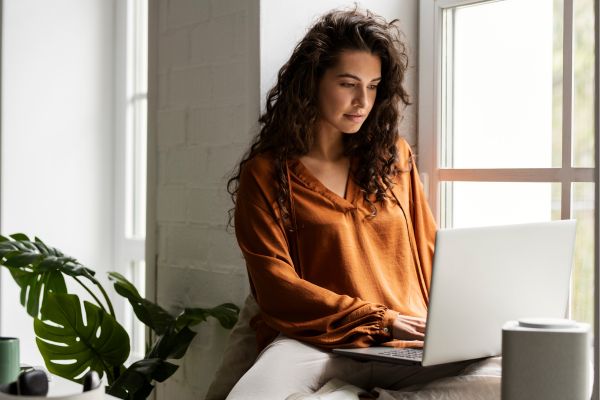 Lady, sitting at a windowsill, using a laptop