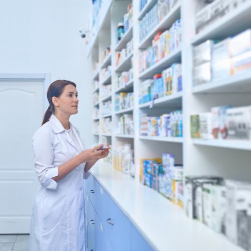 pharmacist next to a shelf of medicines