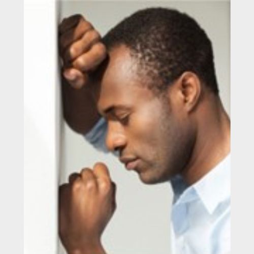 a man resting is head on a wall, looking sad