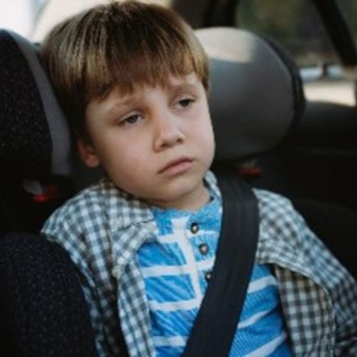 boy looking sad sitting at the back of a car