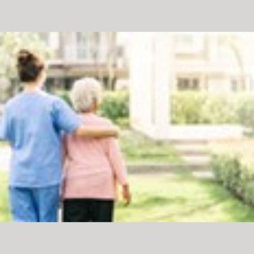 an elderly lady with a care worker standing outside the care home