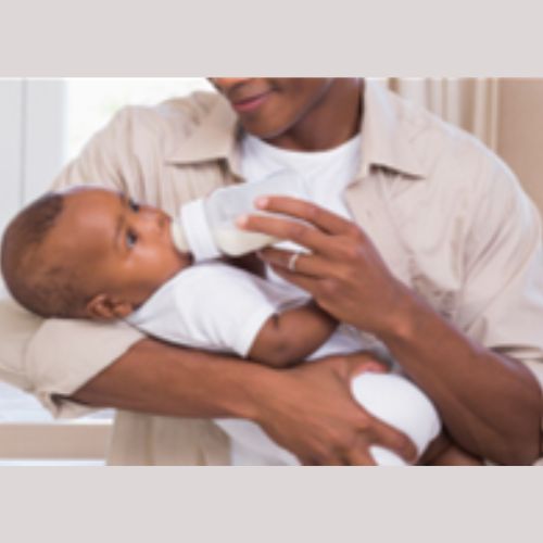 a person bottle feeding a baby