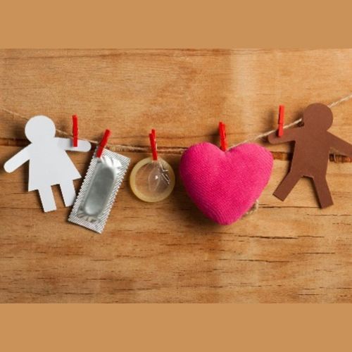 papercut of a man and woman, heart and devices used as contraception hanging from a string
