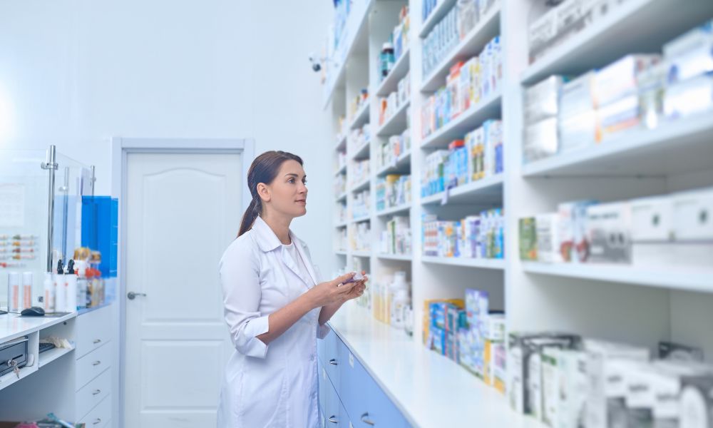 pharmacist next to a shelf of medicines