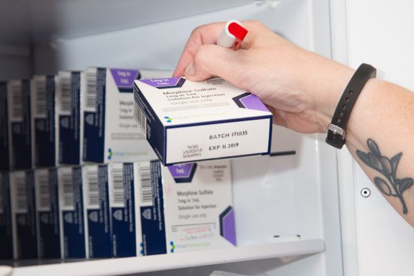 pharmacist picking a pack of tablets from a shelf