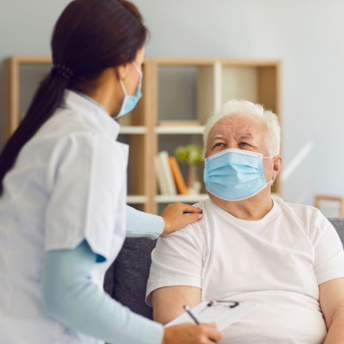 healthcare professional with elderly patient - both wearing masks