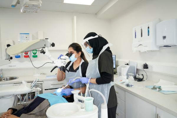 2 dental professionals doing a procedure on a patient