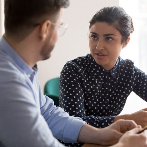 A woman and a man sittig at a desk having a conversation