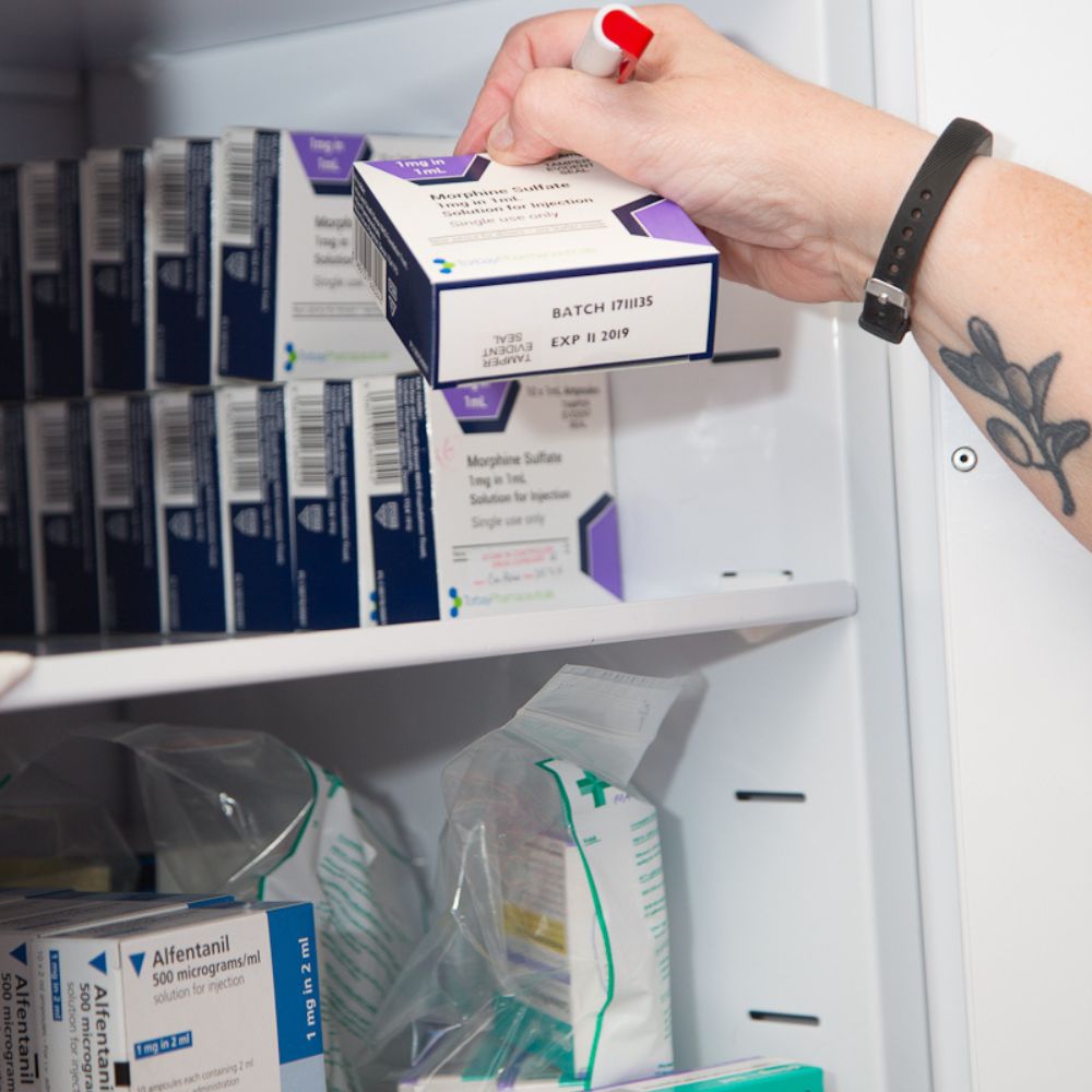 Person picking a pack of tablets out of a medication cupboard