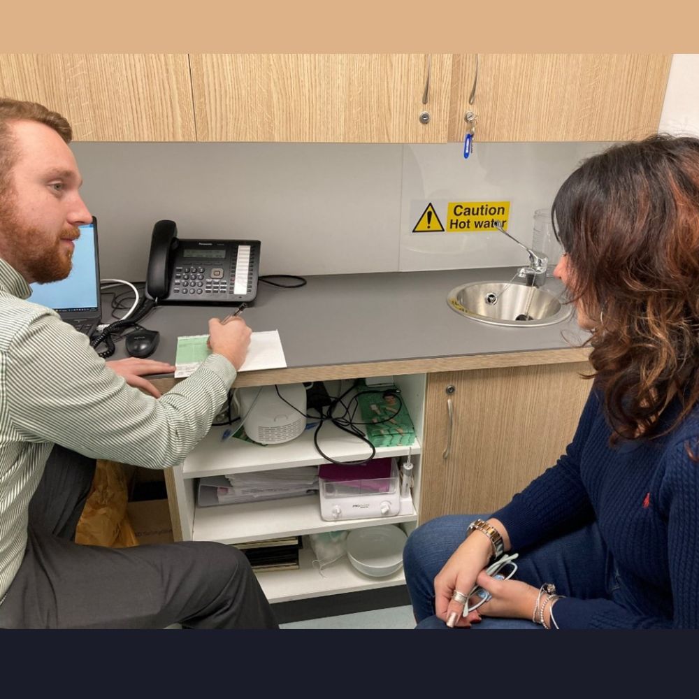 Healthcare professional filling out a prescription for a patient following a consultation