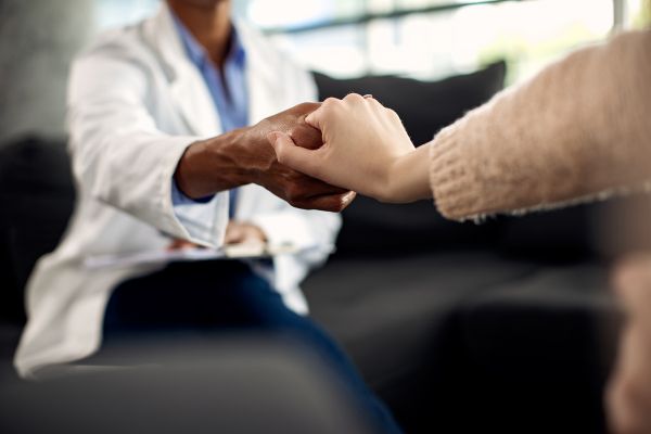 close up shot of a healthcare professional holding the hand of a patient