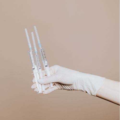 hand holding 3 syringes on a brown background