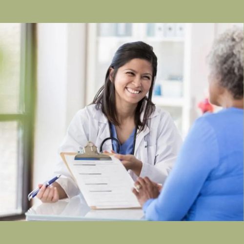 Smiling doctor holds a clipboard and speaks with an older woman during a consultation