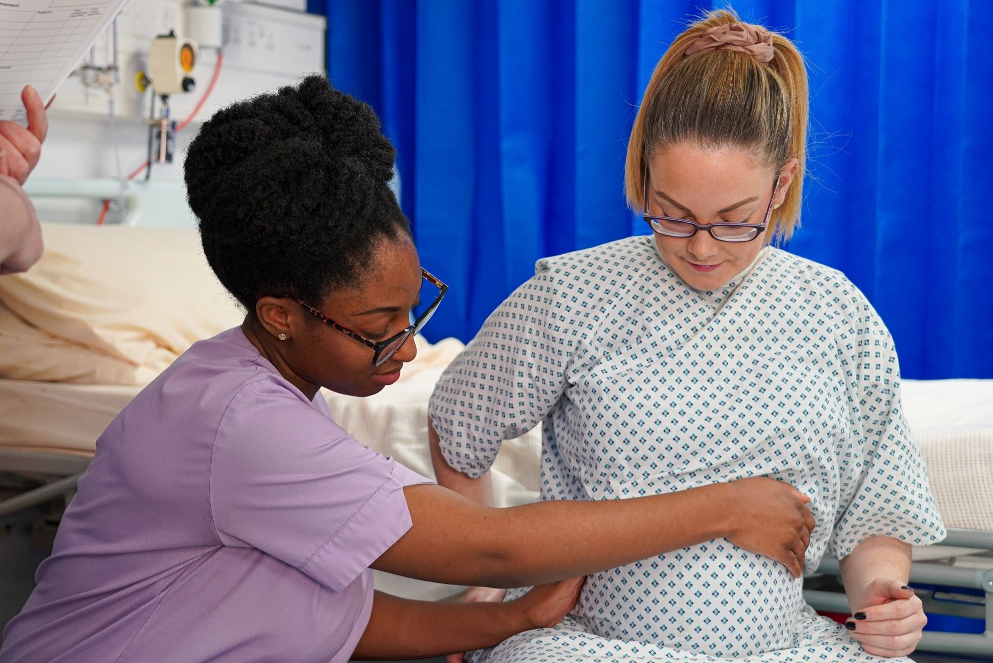 Female medical staff examinating pregnant patient belly with her hands