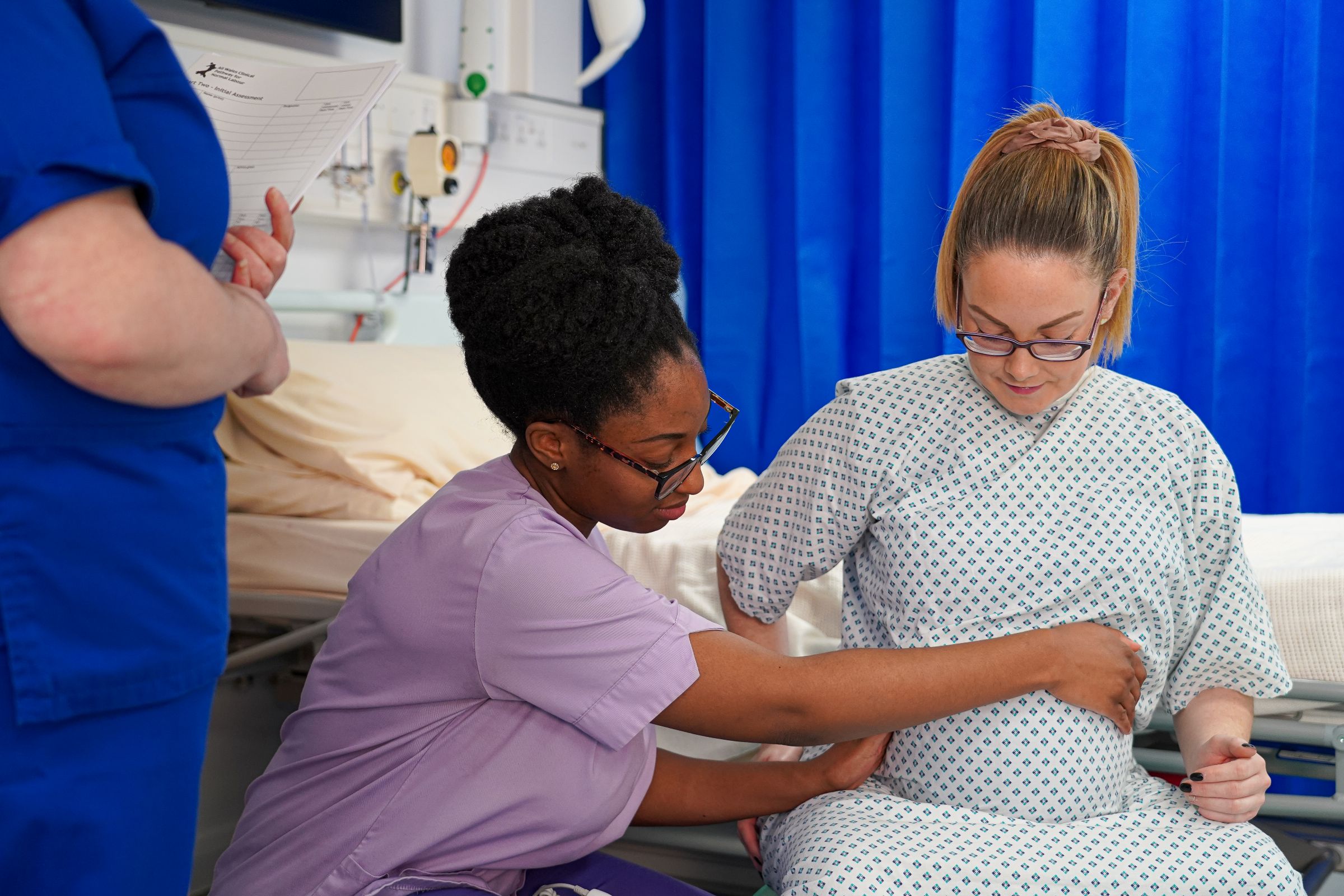 Female medical staff holding pregnant patient belly with her hands