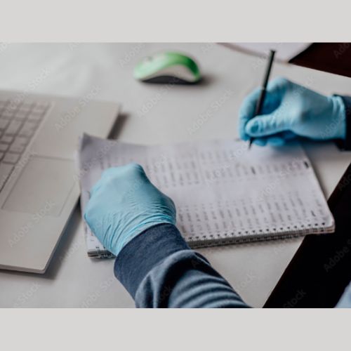 person wearing latex gloves, doing claculations in a book