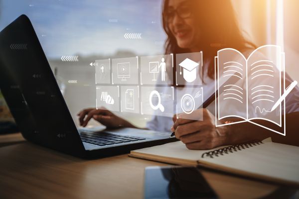 lady on a laptop, writing in a notebook. There are icons around the image