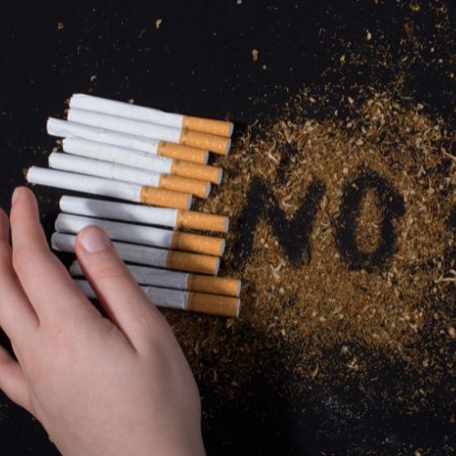 Cigarettes next to lose tobacco with no spelt out on a black background